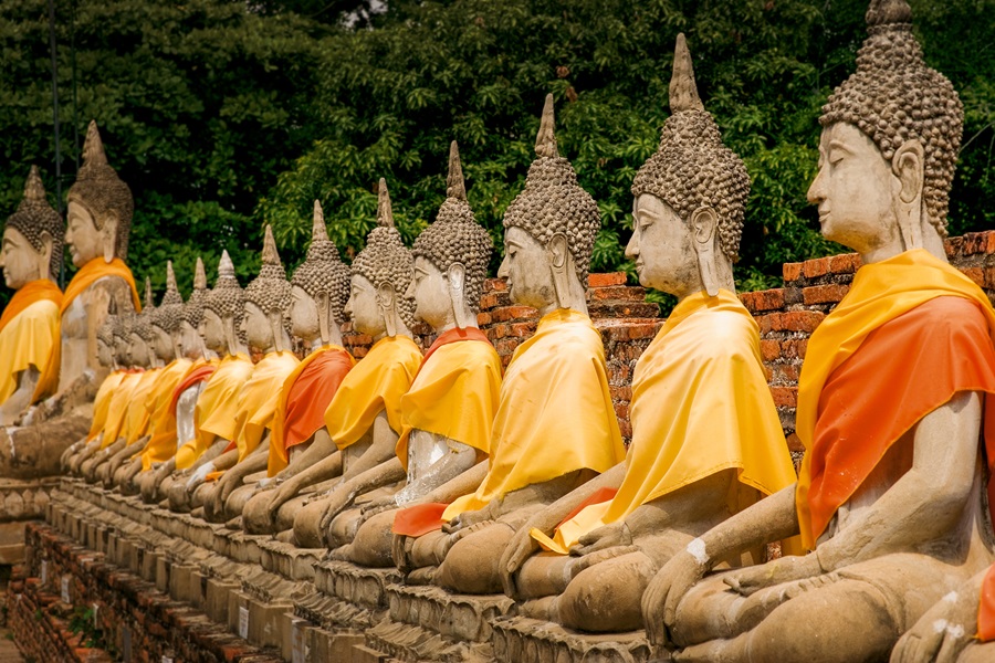 Rij aangeklede bhoedda beelden nabij Tempel, te zien bij reizen naar Thailand